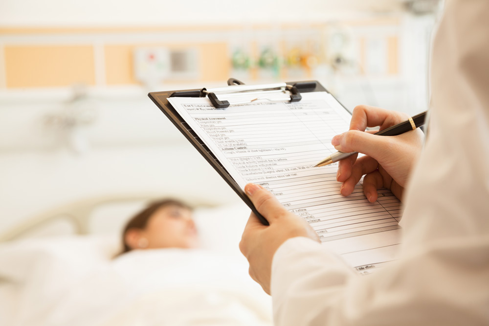Doctor Noting Document About Patient In Hospital Bed